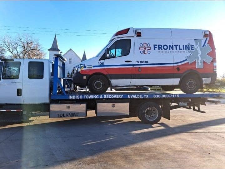 Indigo flatbed transporting a Frontline medical transport ambulance